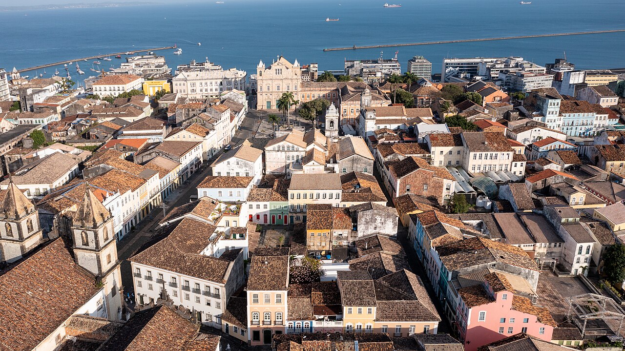 Vista aérea do Centro Histórico de Salvador: telhados coloniais, Terreiro de Jesus e a baía ao fundo.